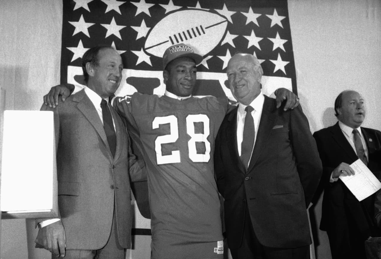 1984 — IRVING FRYAR
<b>New England Patriots</b> | WR Nebraska
<br>El receptor Irving Fryar (28) posa para una foto con su madre Allene McGhee y el dueño de los Patriotas de Nueva Inglaterra Bill Sullivan durante el Draft de la NFL el 1° de mayo de 1984 en Nueva York. Fryar fue el primer receptor abierto seleccionado con la primera selección global en un draft de la NFL. (Foto AP / Paul Spinelli)