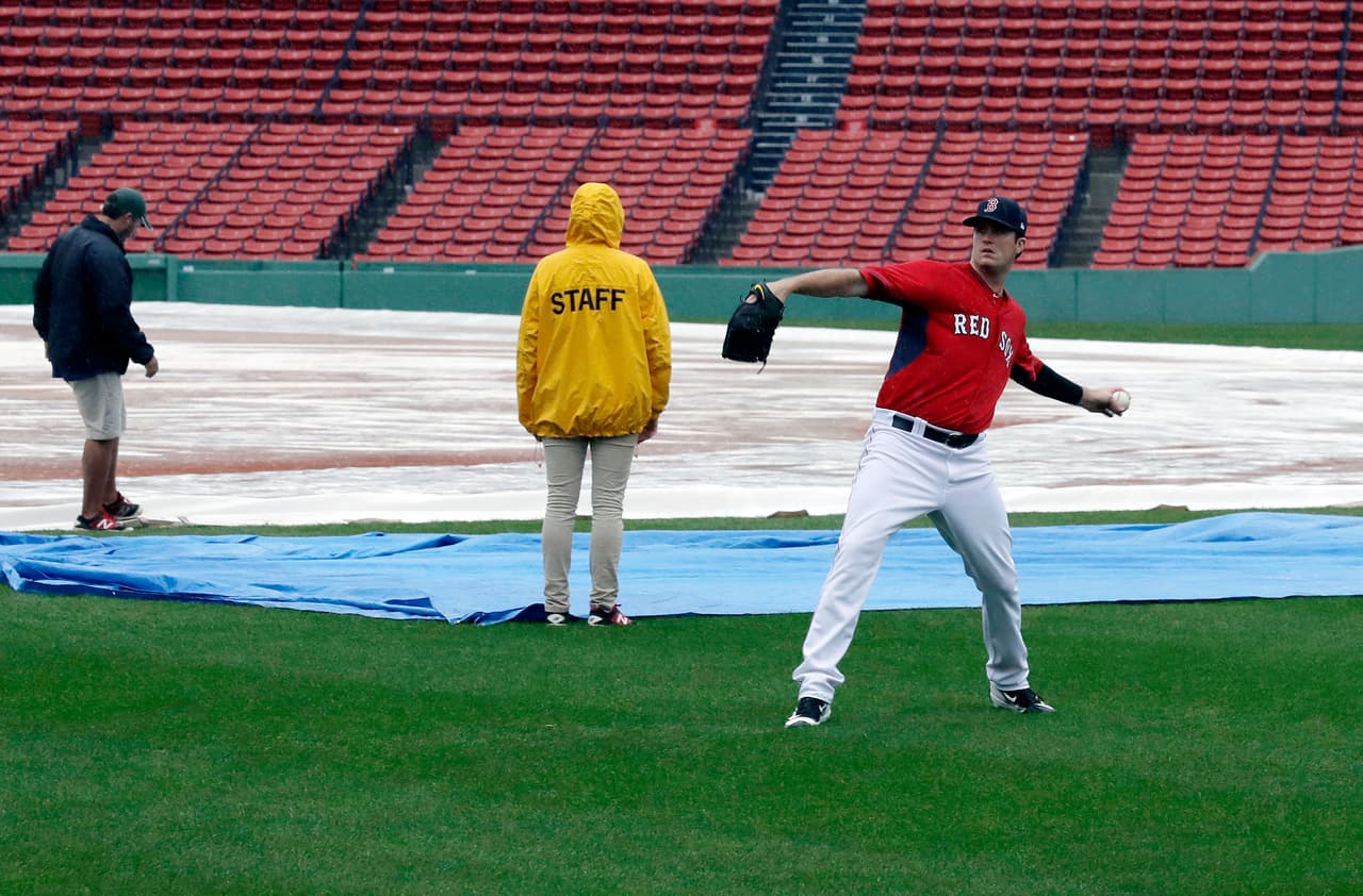 Boston Red Sox pitcher Drew Pomeranz tosses a baseball in the outfield in front of grounds crew workers at Fenway Park, Sunday, Oct. 9, 2016, in Boston. Rain postponed Sunday's scheduled Game 3 of baseball's American League Division Series between the Cleveland Indians and the Red Sox until Monday. (AP Photo/Charles Krupa)