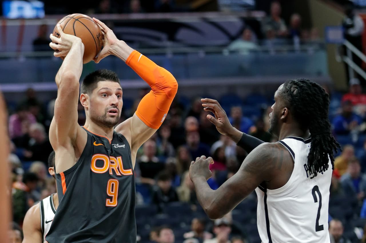 Magic 101-89 Nets. Nikola Vucevic pasa el balón ante la marca de Taurean Prince que sólo lo contempla.