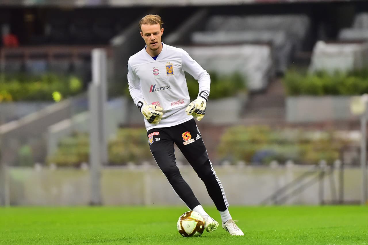 El arquero sale a calentar y hace movimientos con el balón.