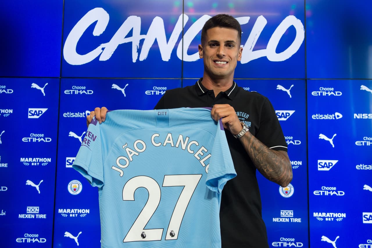 Manchester City's newly signed Portuguese defender Joao Cancelo poses with his club shirt during his unveiling at the City Football Academy in Manchester on August 8, 2019. (Photo by Oli SCARFF / AFP) (Photo credit should read OLI SCARFF/AFP/Getty Images)