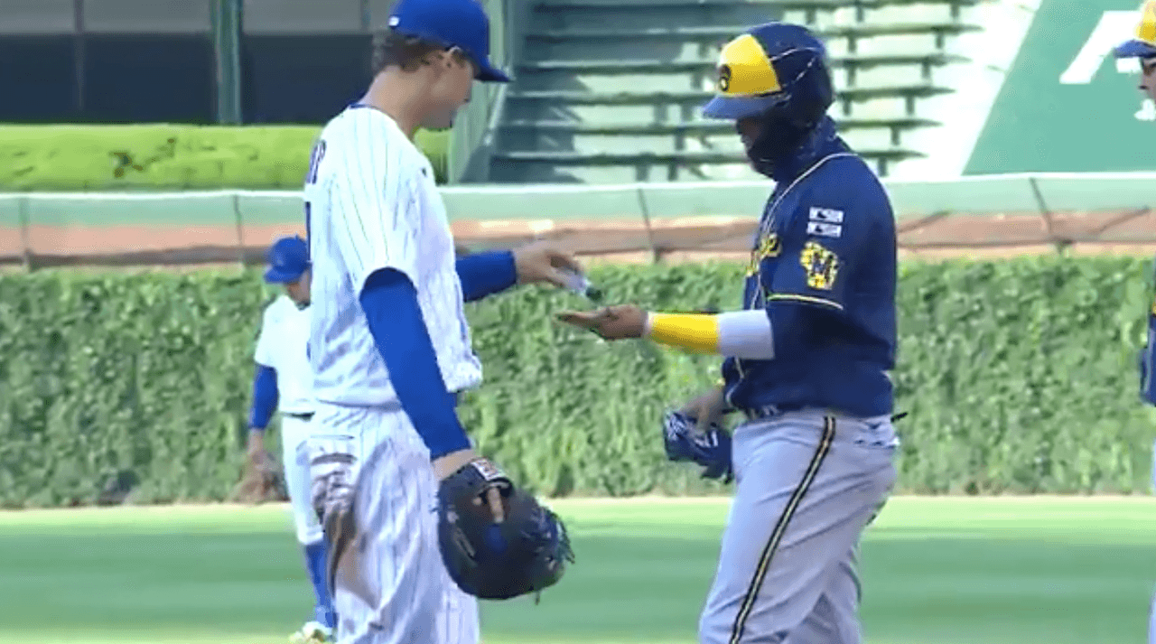 Anthony Rizzo, de los Cubs, da gel antibacterial a Orlando Arcia, de Brewers.