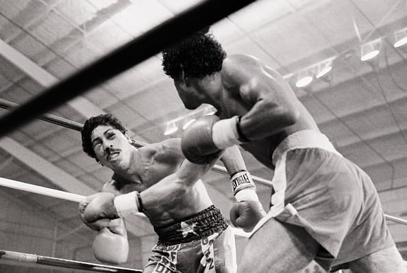 (Original Caption) 8/21/1981-Las Vegas, NV- Puffy-eyed Wilfredo Gomez (L) looks dazed after being hit by defending champion Salvador Sanchez for the last time during eighth round action of their title bout. Referee Carlos Padilla stepped to stop the fight after this blow to the head of Gomez. Sanchez won in the eighth round TKO to retain his title.