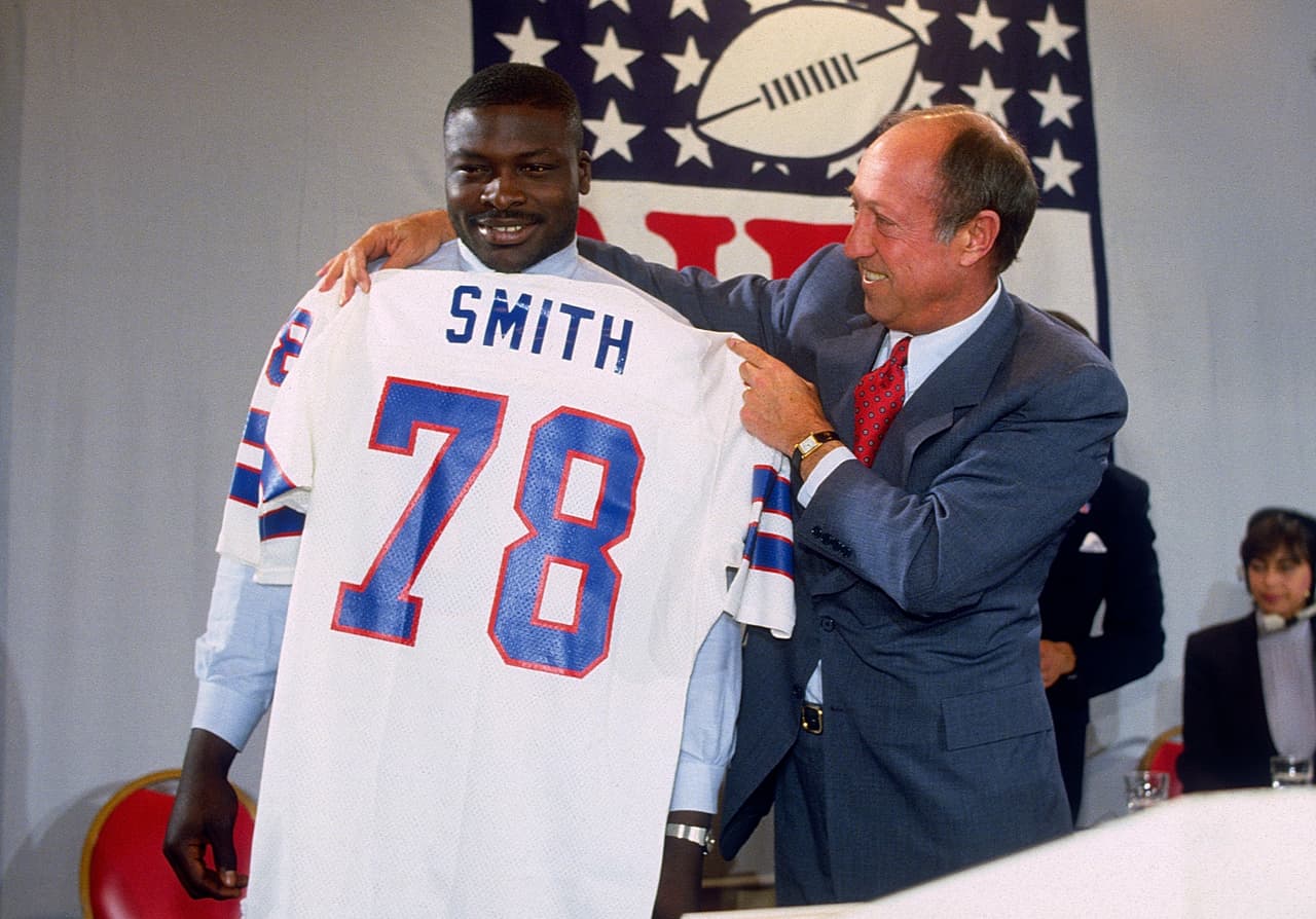 1985 — BRUCE SMITH
<b>Buffalo Bills</b> | DT Virginia Tech
<br>El comisionado de la NFL, Pete Rozelle, sostiene el nuevo jersey para el recién elegido por Buffalo, Bruce Smith (78) ala defensiva, primera selección de los Bills y la selección número uno global de la NFL celebrado el 30 de abril de 1985 en Nueva York. (Foto AP / Paul Spinelli)